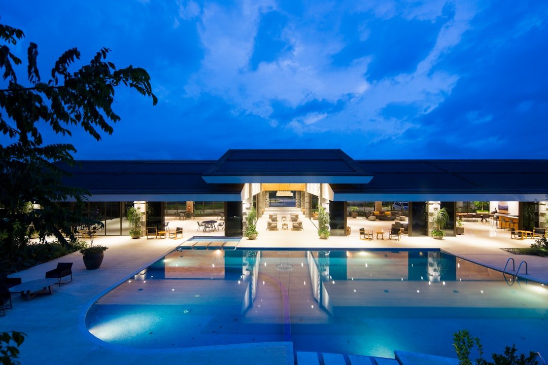 blue-body-of-water-in-front-of-building-near-trees-during-nighttime-m7gddpqjowg